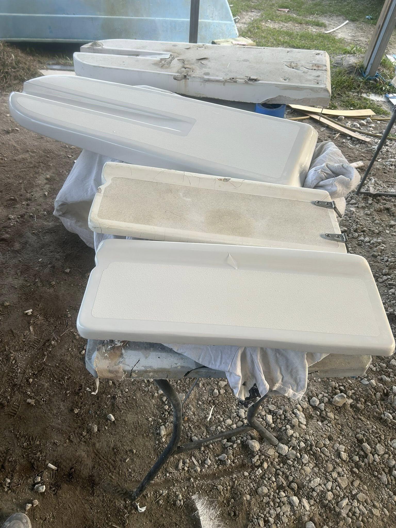 Multiple custom-fabricated fiberglass console panels and hatches stacked on a workbench after refinishing