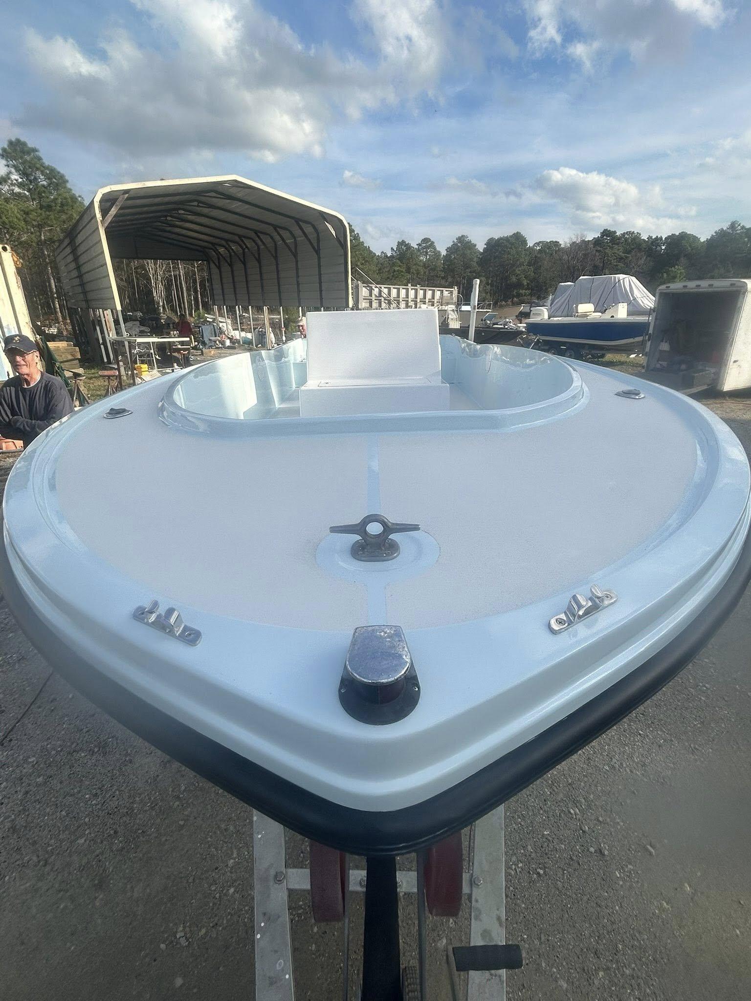 Refinished fiberglass bowrider on a trailer at dusk with a freshly painted white topside and clean cap line
